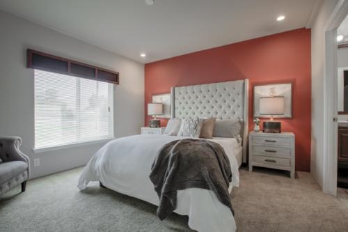 A bedroom with orange walls and a white bed.