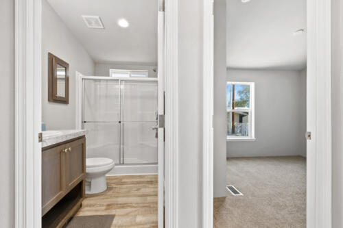A bathroom with a door leading to a shower.