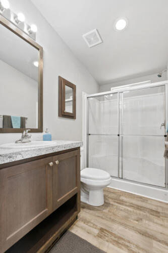 A bathroom with wood floors and a shower stall.