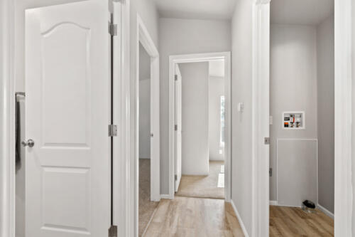 A hallway with white doors and wood floors.