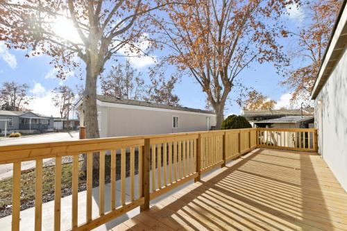 The deck of a mobile home with a wooden railing.