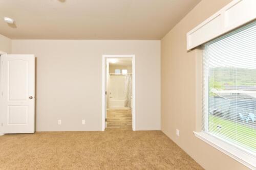 An empty room with tan carpet and a door.