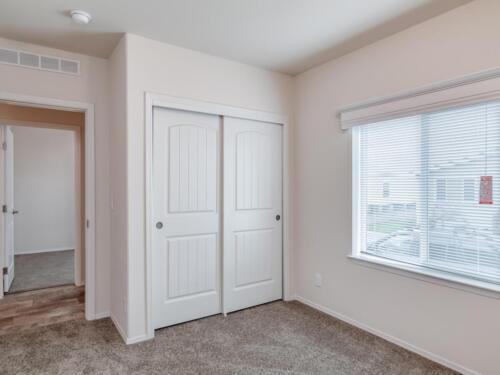 An empty room with closets and a window.