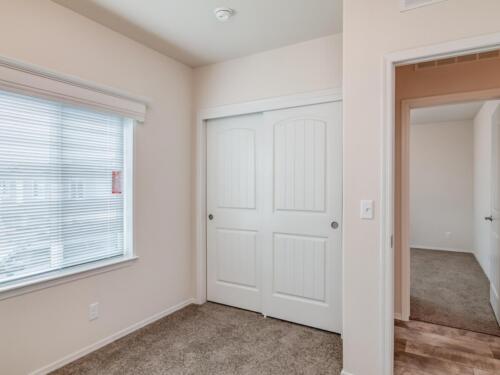 An empty room with two closets and a window.