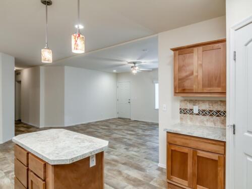 An empty kitchen with wood cabinets and granite counter tops.
