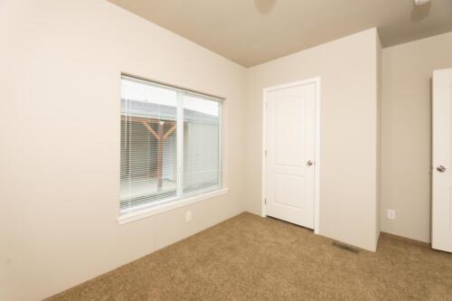 An empty room with tan carpet and a sliding door.