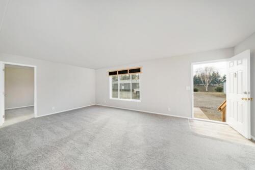 An empty room with gray carpet and a sliding door.