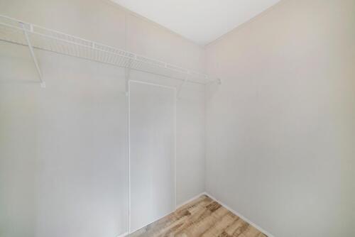 An empty room with a wooden floor and a white closet.